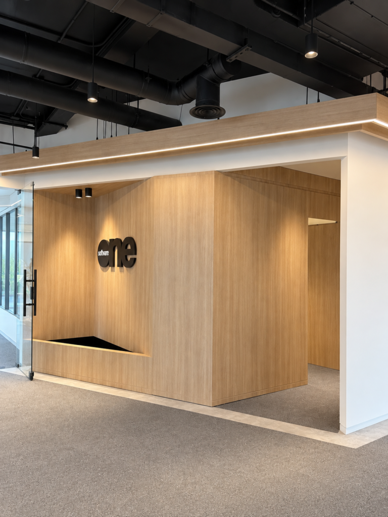 Minimalist timber reception cladding at One Software offices featuring custom wood paneling and office branding signage